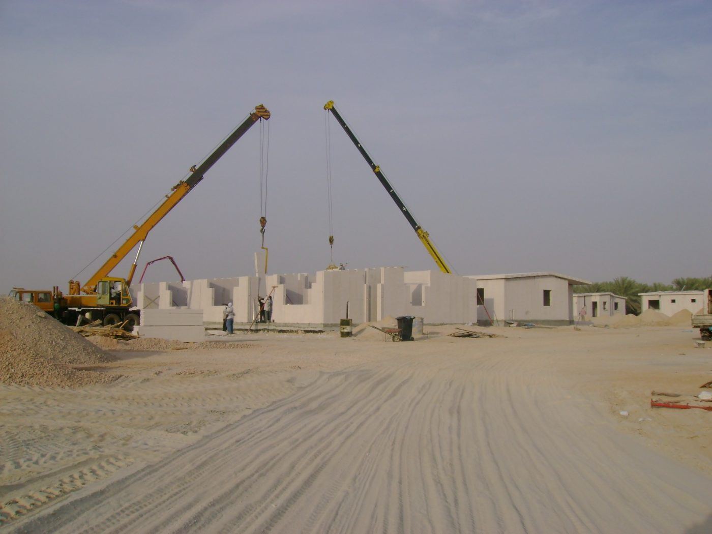 Twin mobile cranes erecting lightweight precast panels on site